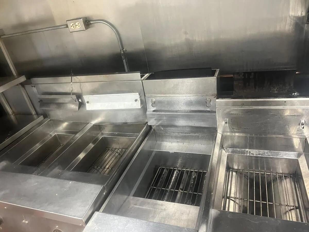 Stainless steel fryers and grill line in a commercial kitchen cleaned by The OMG Cleaning Services