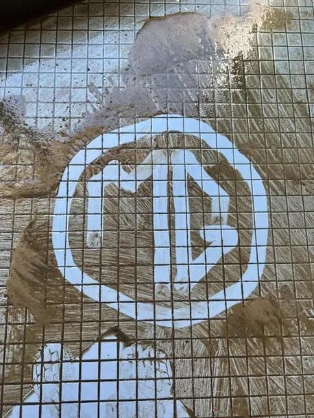 A commercial kitchen grease trap and floor grate being cleaned by The OMG Cleaning Services